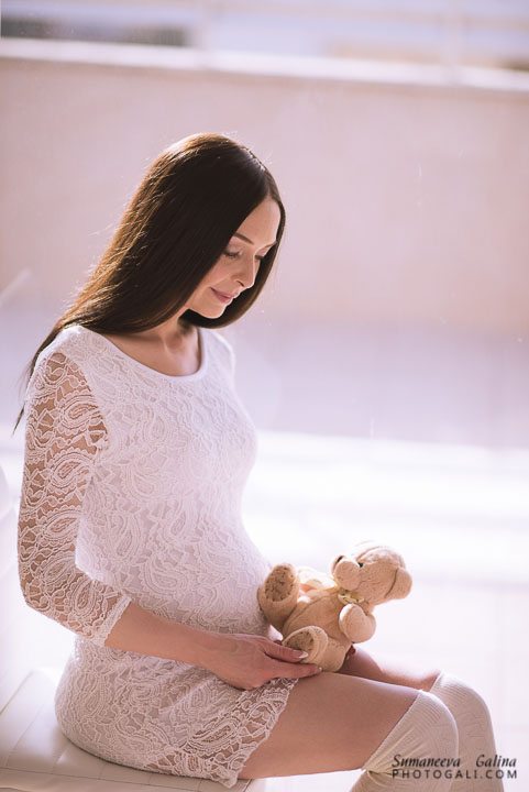 אישה בהריון יושבת עם דובי